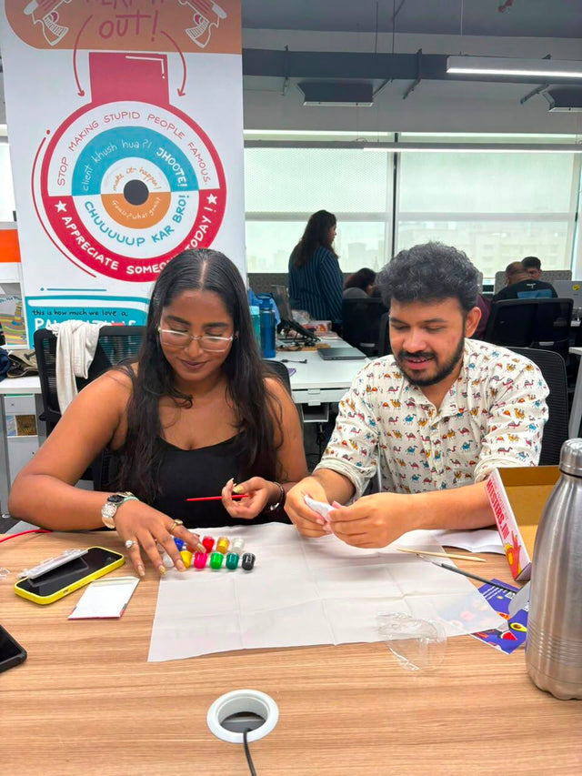 Two colleagues at a table working through their kits, paints and materials spread out between them