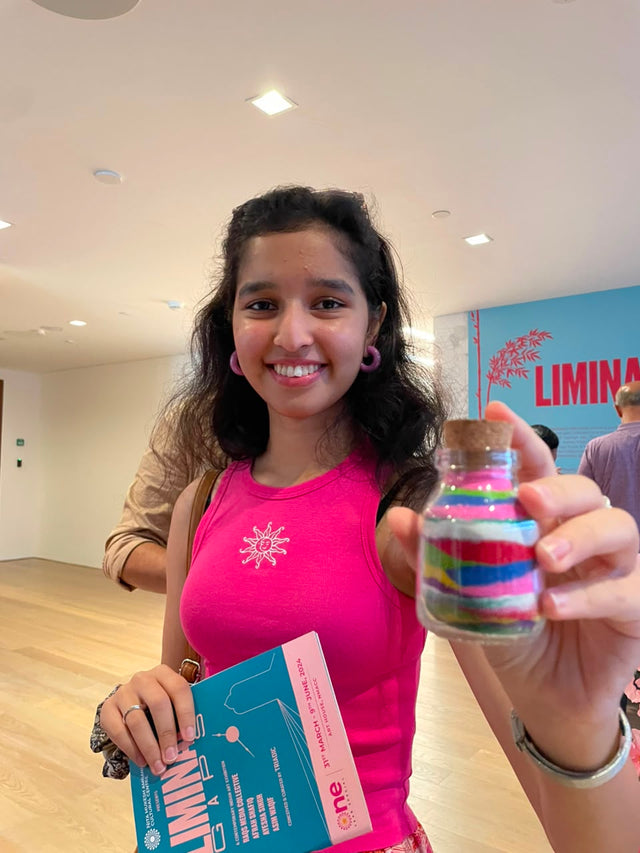 A colleague holding up a jar layered with coloured sand, her kit box still in her other hand