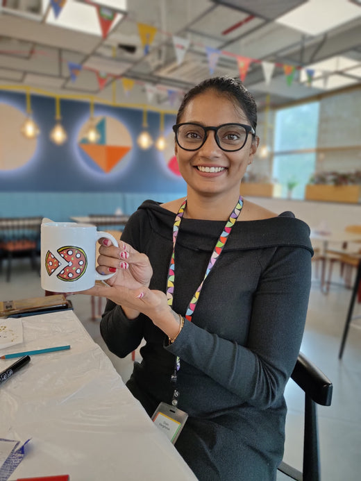 A guest holding up the mug she hand-painted at an office session
