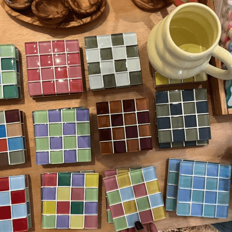 Loose mosaic tiles laid out beside a finished coaster - the consumables a refill replaces