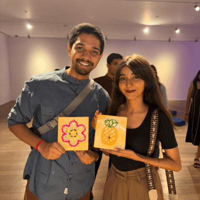 Two guests holding the tile coasters they painted at a Kitsters event