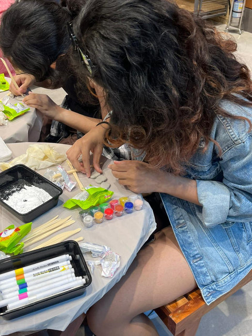 Hands shaping and painting at a Kitsters craft table